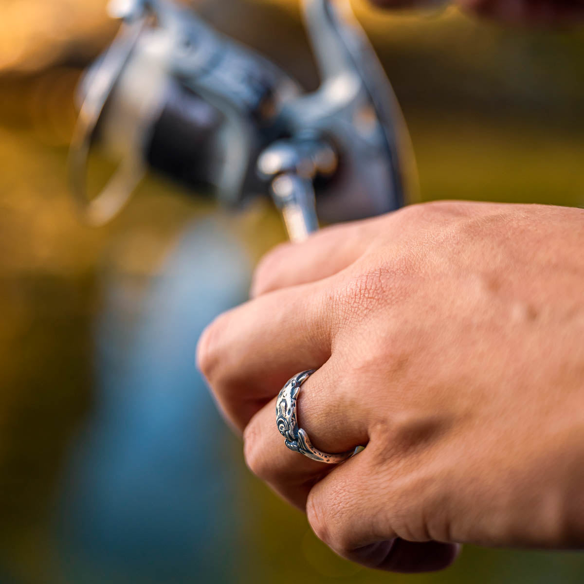 Hand holding a fishing rod with a blurred background