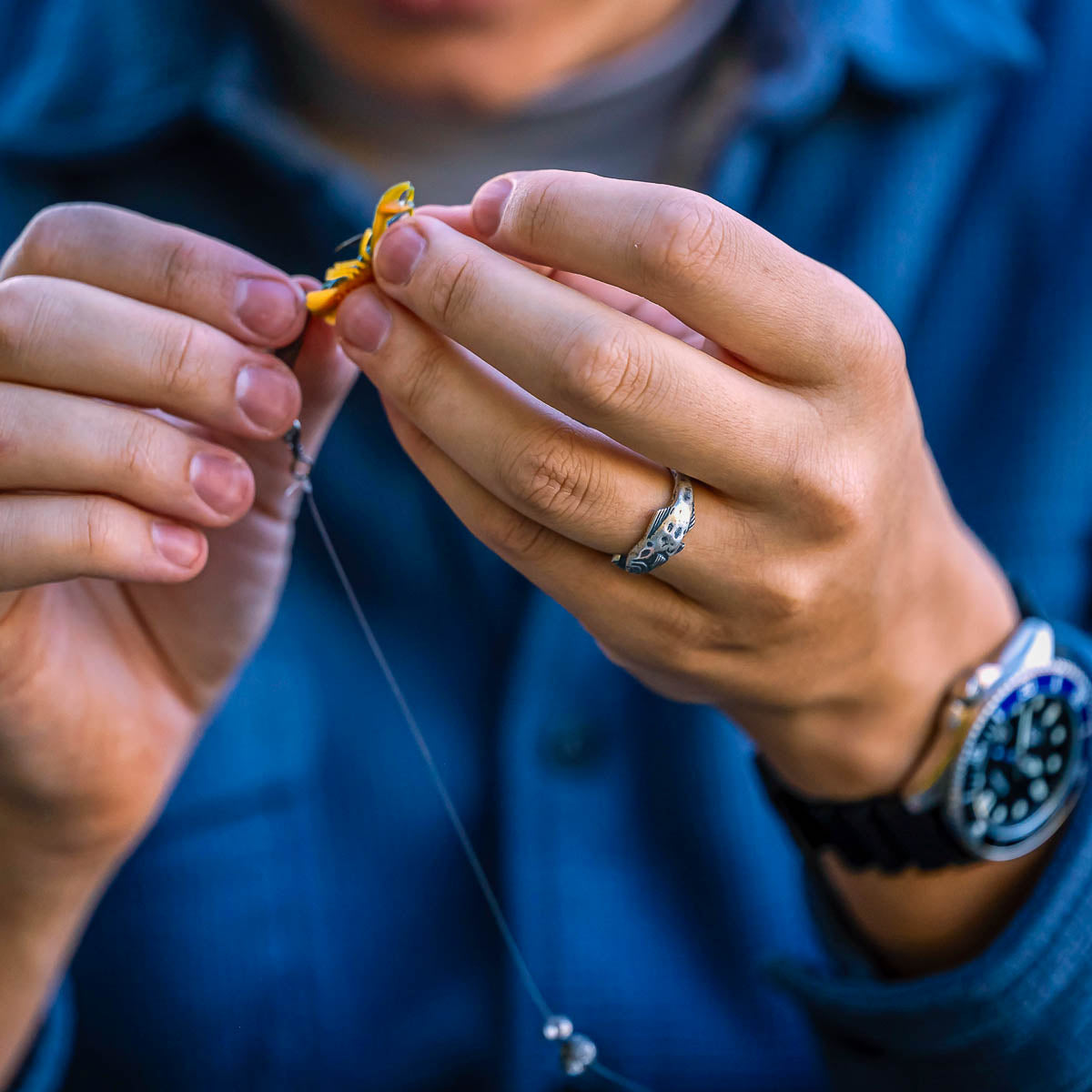 Close-up of hands tying a fishing knot with a blurred background