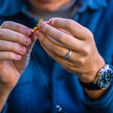 Close-up of hands tying a fishing knot with a blurred background