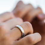 Close-up of a hand wearing a silver ring with a blurred background
