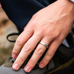 Hand with a ring on the ring finger in front of a hiking boot