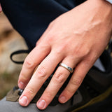 Hand with a ring on the ring finger in front of a hiking boot