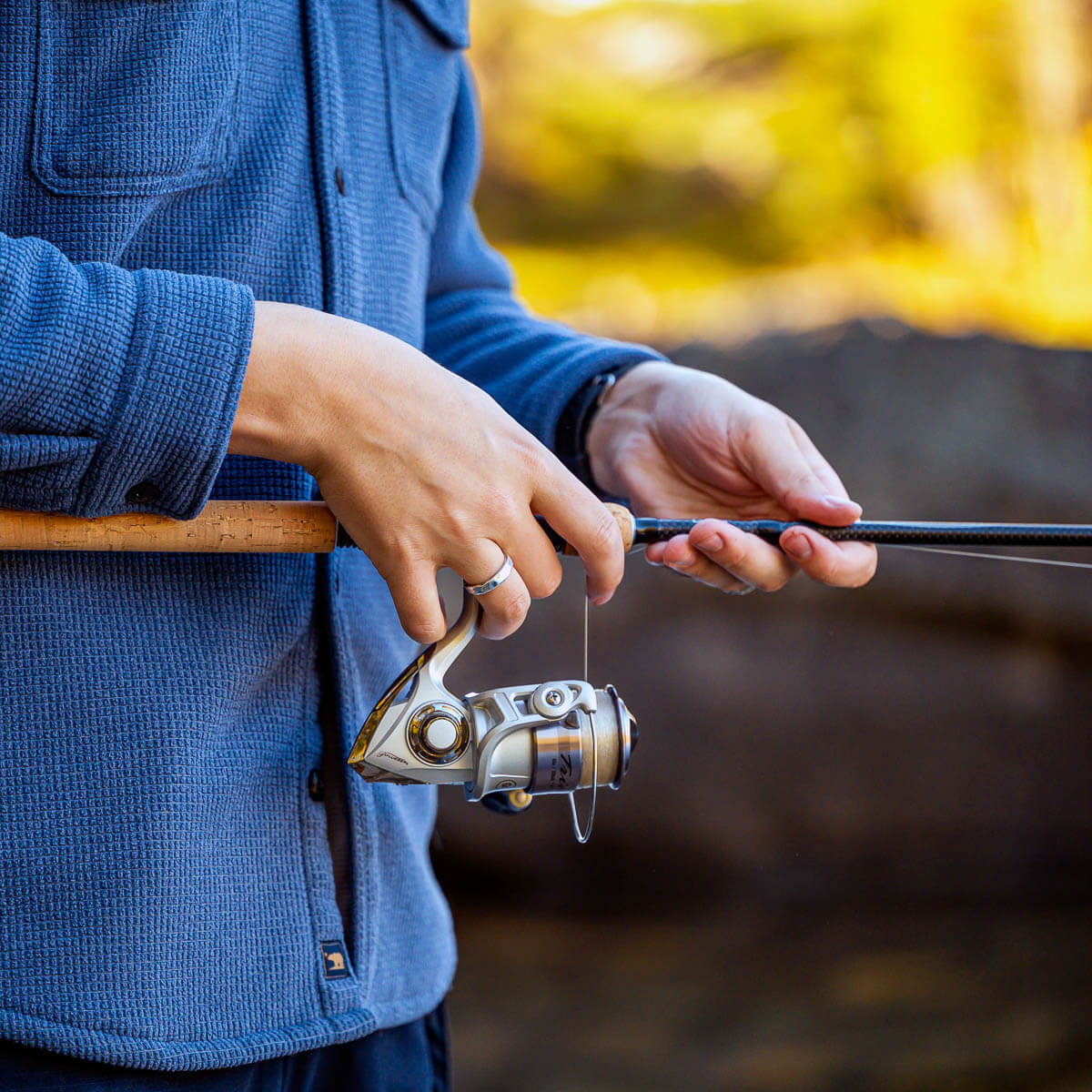 Person holding a fishing rod with a blurred natural background