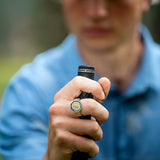 Person wearing a lion signet ring holding a putter grip outdoors