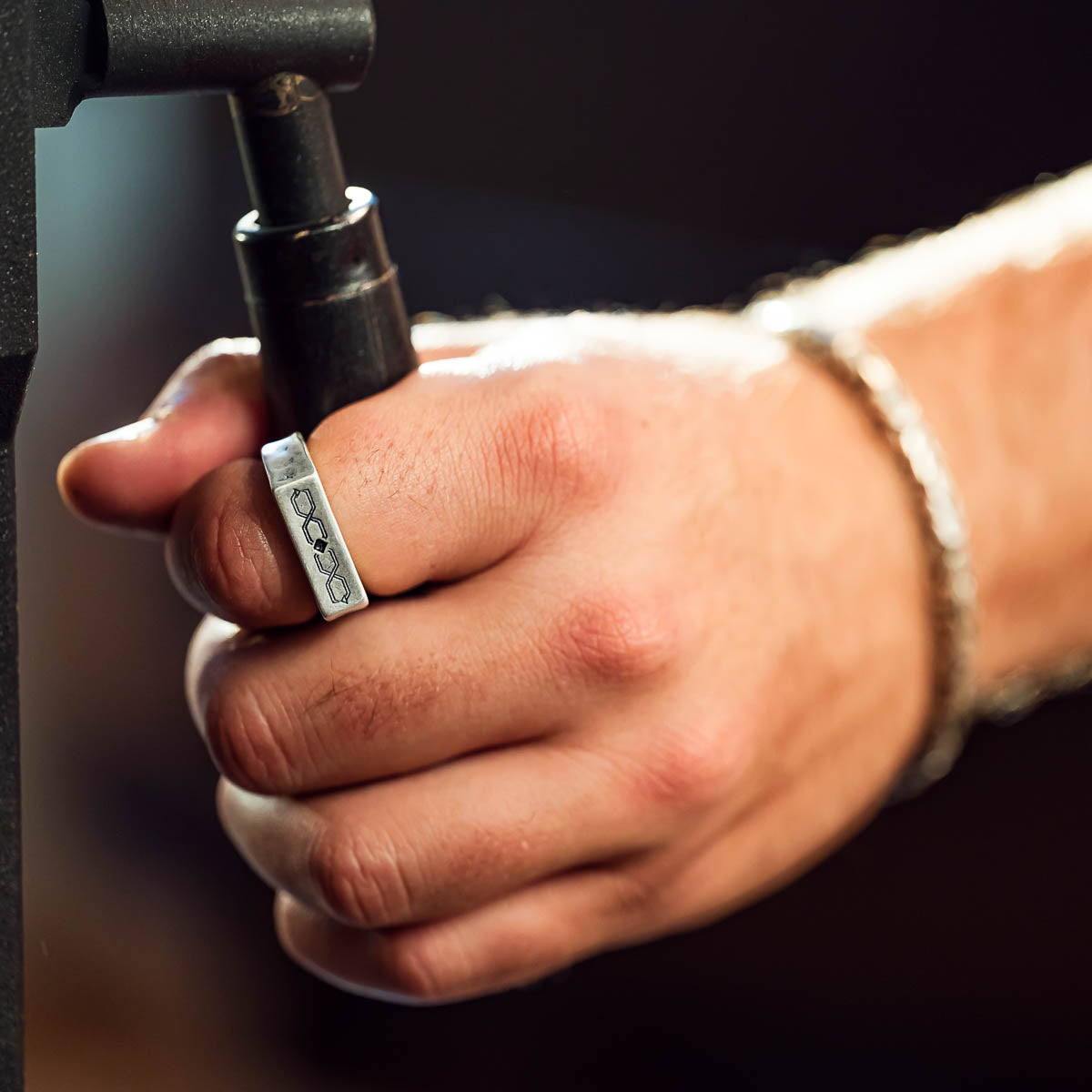Hand wearing a silver ring with a blurred background